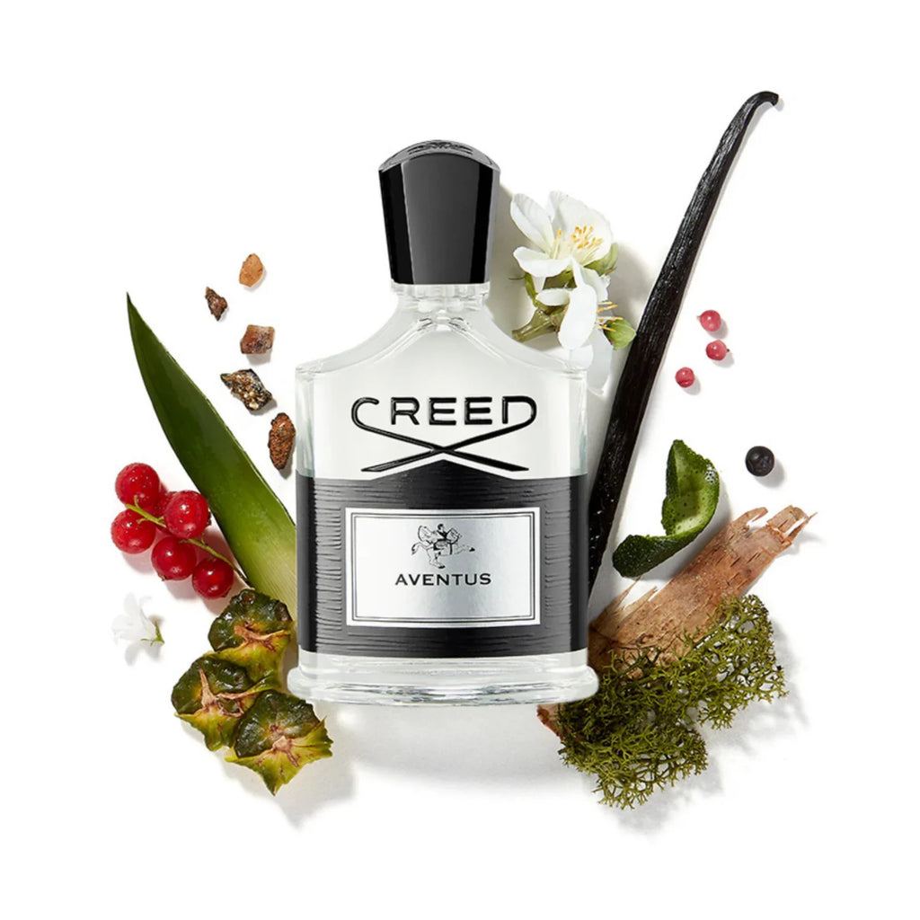 Creed Aventus bottle surrounded by pineapple, blackcurrant, birch bark and moss, the materials behind its fruity and smoky accords